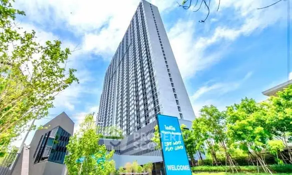 Modern high-rise building with lush greenery and clear blue sky, ideal for urban living.