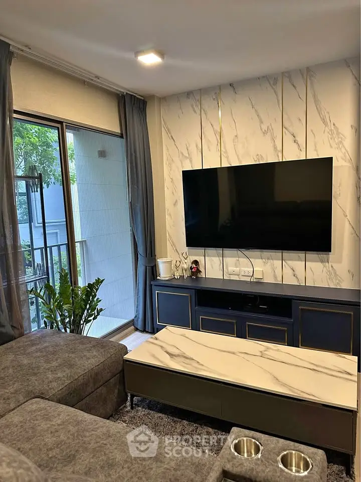 Modern living room with marble accents and large TV, featuring a cozy sofa and balcony view.