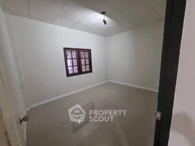 Spacious empty room with tiled floor and window, ideal for customization.