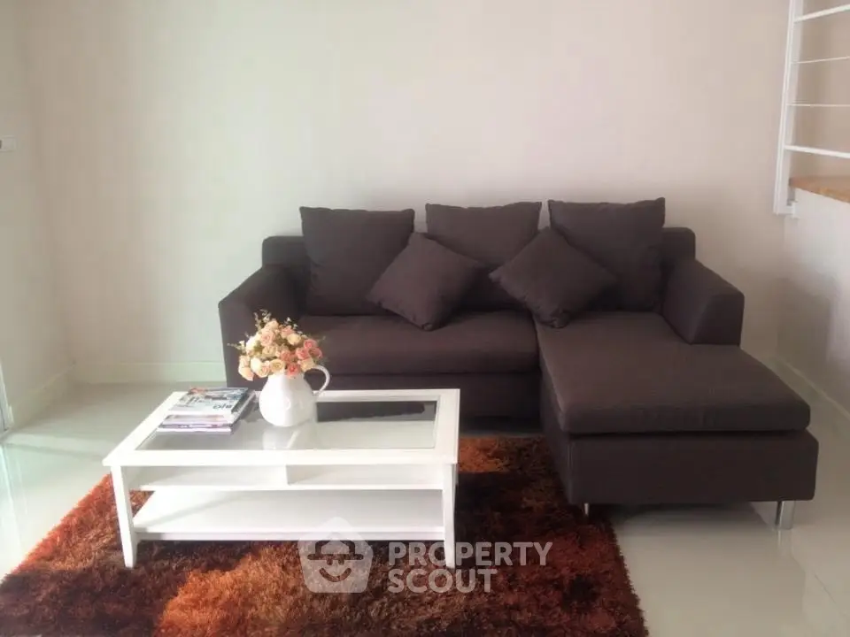 Cozy living room with dark sofa, white coffee table, and plush rug, perfect for relaxation.