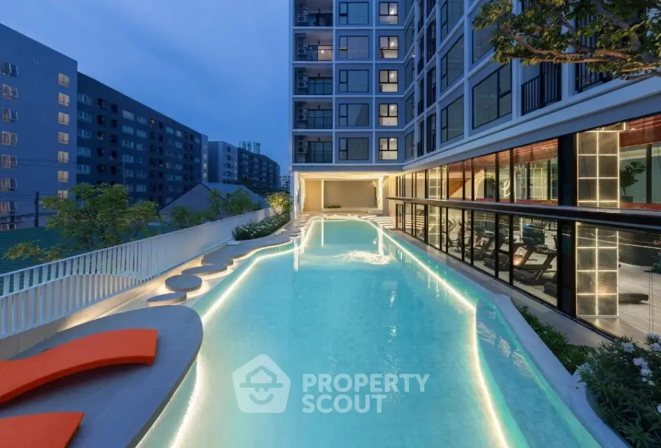 Luxurious apartment complex with illuminated pool and modern gym facilities at dusk.