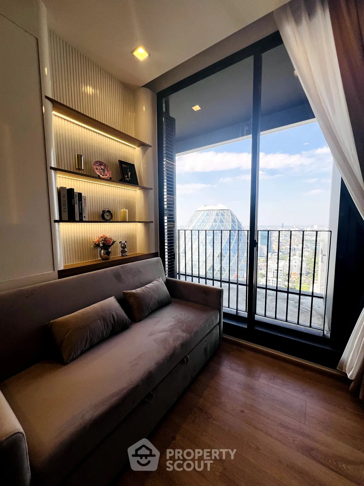 Stylish living room with balcony and city view, featuring modern decor and cozy seating.