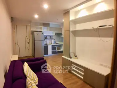 Modern living room with open kitchen and stylish purple sofa in a cozy apartment.