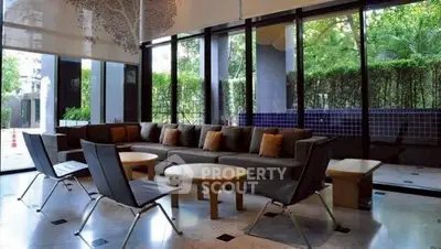 Spacious modern living room with large windows and stylish furniture, offering a serene garden view.