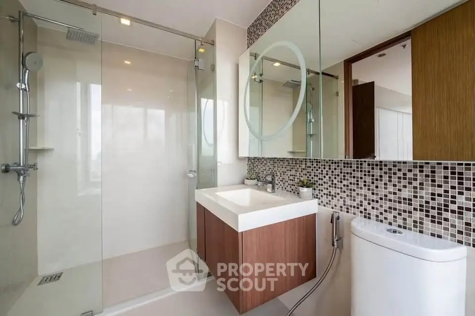 Modern bathroom with glass shower and stylish vanity in luxury apartment.
