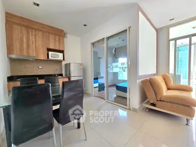 Modern open-plan living room with kitchen and dining area, featuring sleek furniture and large windows.