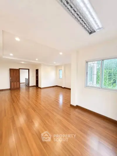 Spacious empty living room with wooden flooring and large window