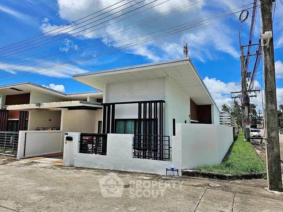 Modern single-story house with sleek design and spacious yard in a suburban neighborhood.