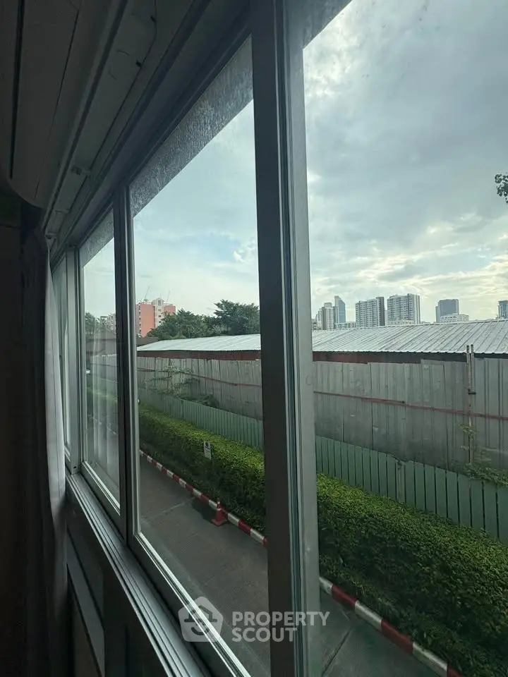 Cityscape view from window with lush greenery and skyline