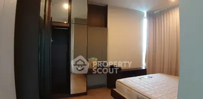 Spacious bedroom with modern furnishings and large mirror in a cozy apartment.
