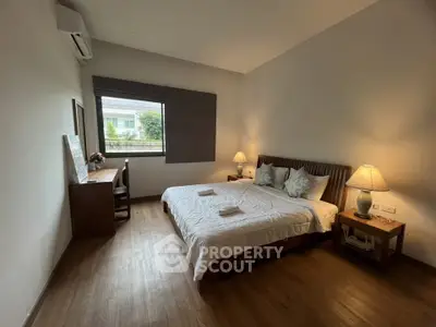 Spacious bedroom with cozy decor and natural light, featuring a large bed and wooden flooring.