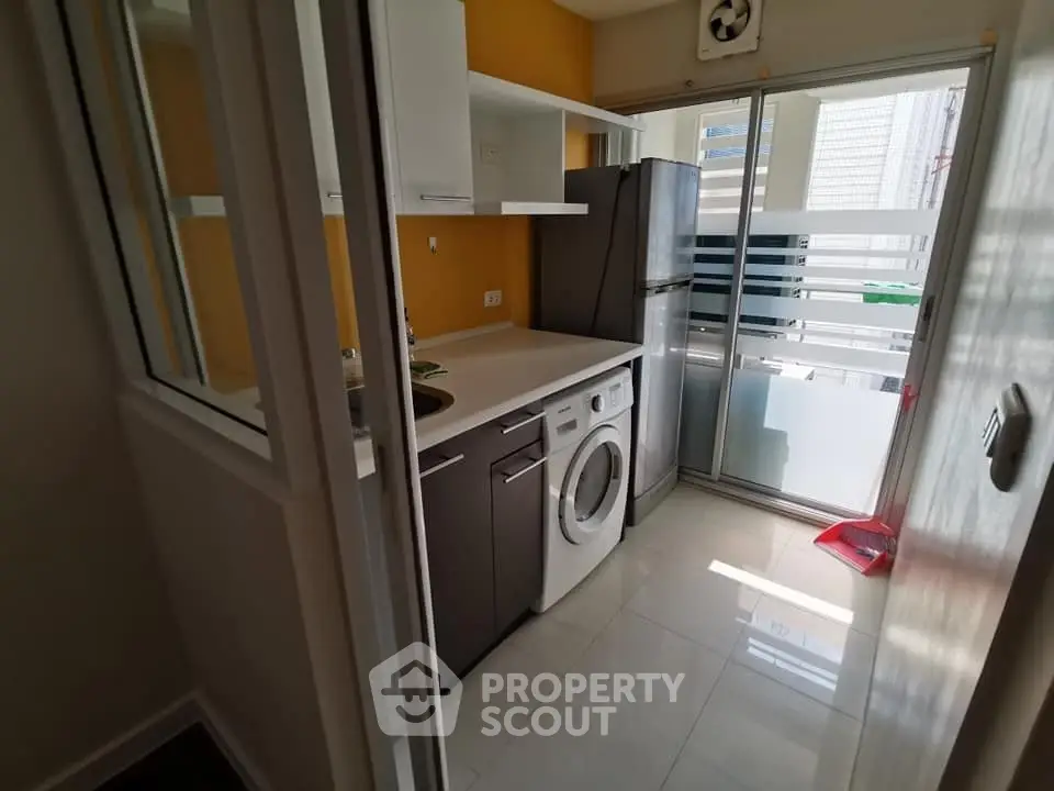 Compact kitchen with modern appliances and washing machine, featuring bright natural light and sleek design.