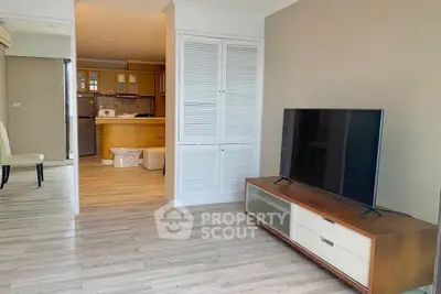 Spacious living room with modern TV setup and open kitchen layout