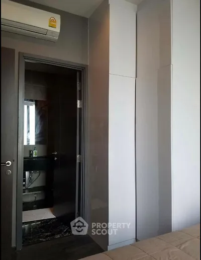 Modern bedroom with sleek closet and view into stylish bathroom