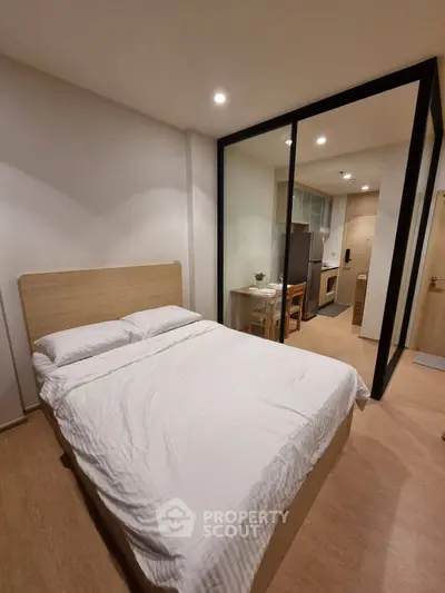 Modern bedroom with glass partition and cozy kitchen area in stylish apartment