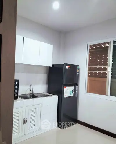 Modern compact kitchen with sleek white cabinets and stainless steel appliances in a cozy apartment.