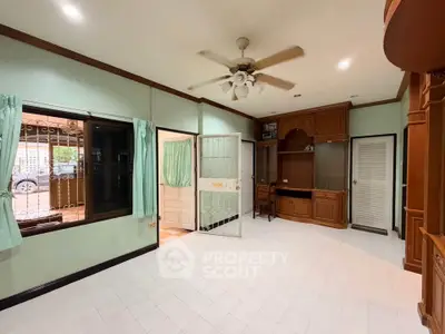 Spacious living room with ceiling fan and built-in wooden cabinets, featuring large windows for natural light.