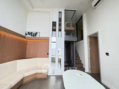 Modern living room with high ceiling and mezzanine, featuring stylish wood paneling and contemporary furniture.