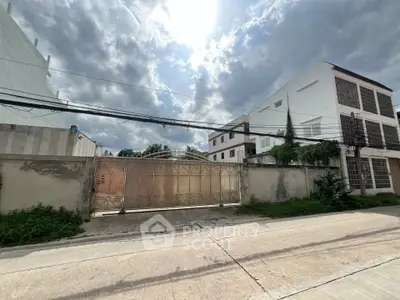 Modern gated property with spacious driveway and contemporary architecture under a bright sky.