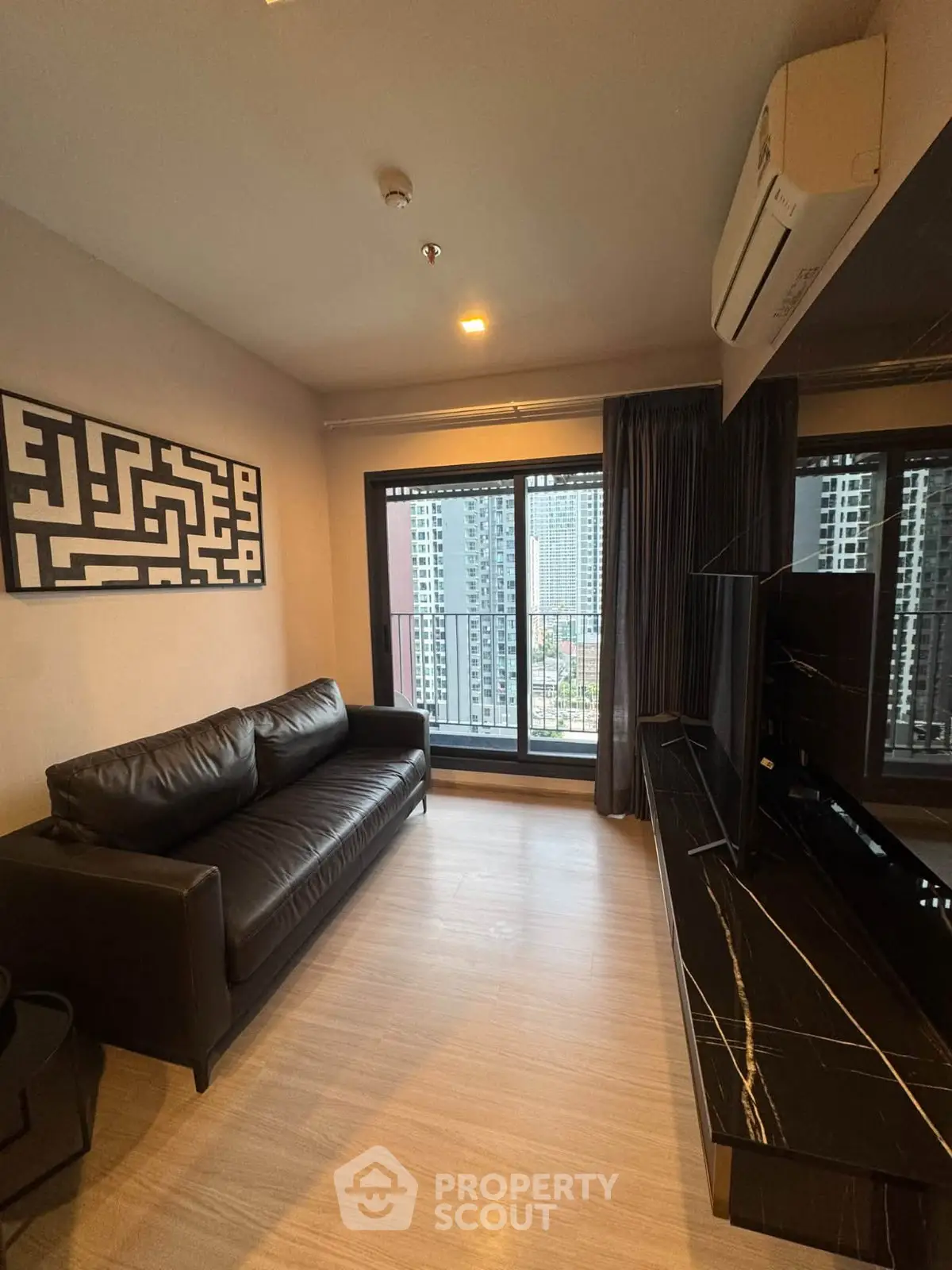 Modern living room with city view, black leather sofa, and sleek decor.