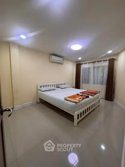 Spacious bedroom with modern design and natural lighting, featuring a comfortable bed and air conditioning.