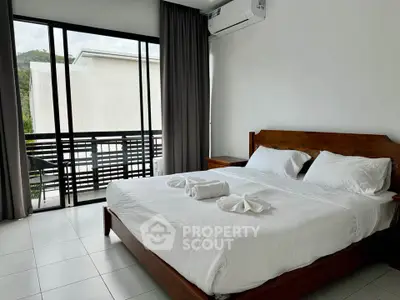 Spacious bedroom with balcony access and modern decor in a serene setting.