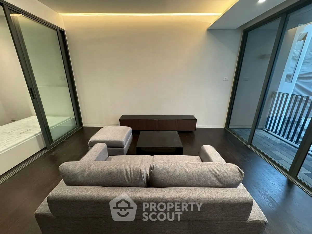 Modern living room with sleek design and large sliding glass doors opening to a balcony.