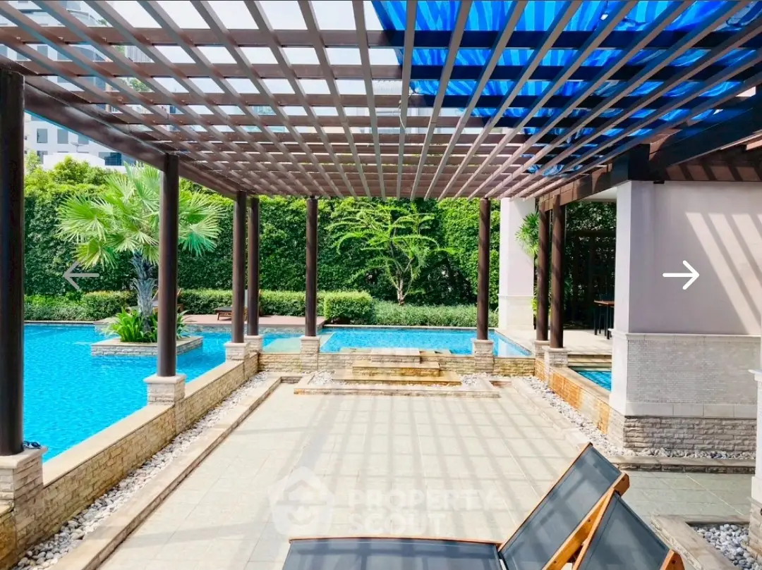 Luxurious poolside area with pergola and lush greenery, perfect for relaxation and leisure.