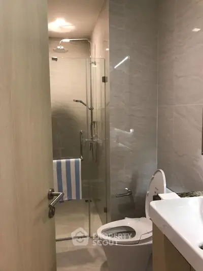 Modern bathroom with glass shower and sleek fixtures in a contemporary apartment.