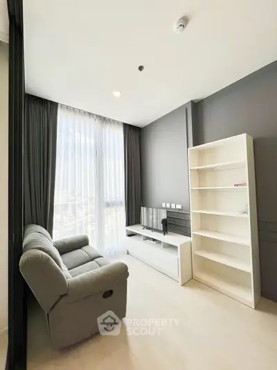 Modern living room with sleek furniture and large window offering natural light