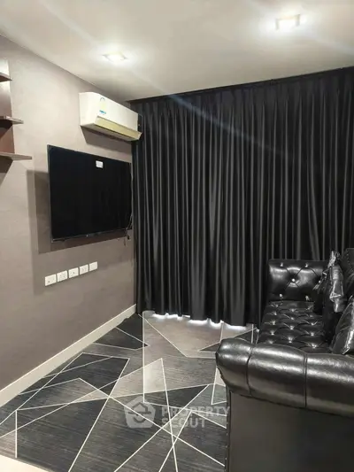 Modern living room with sleek black leather sofa and wall-mounted TV