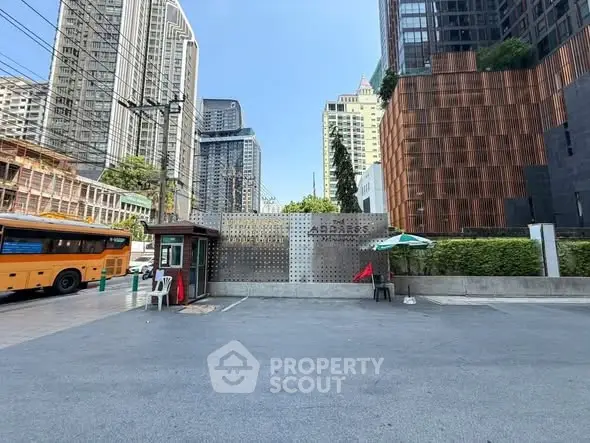 Modern urban building entrance with city skyline backdrop, showcasing contemporary architecture and street view.