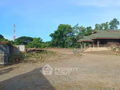 Spacious land with potential for development, featuring a rustic house and lush greenery.