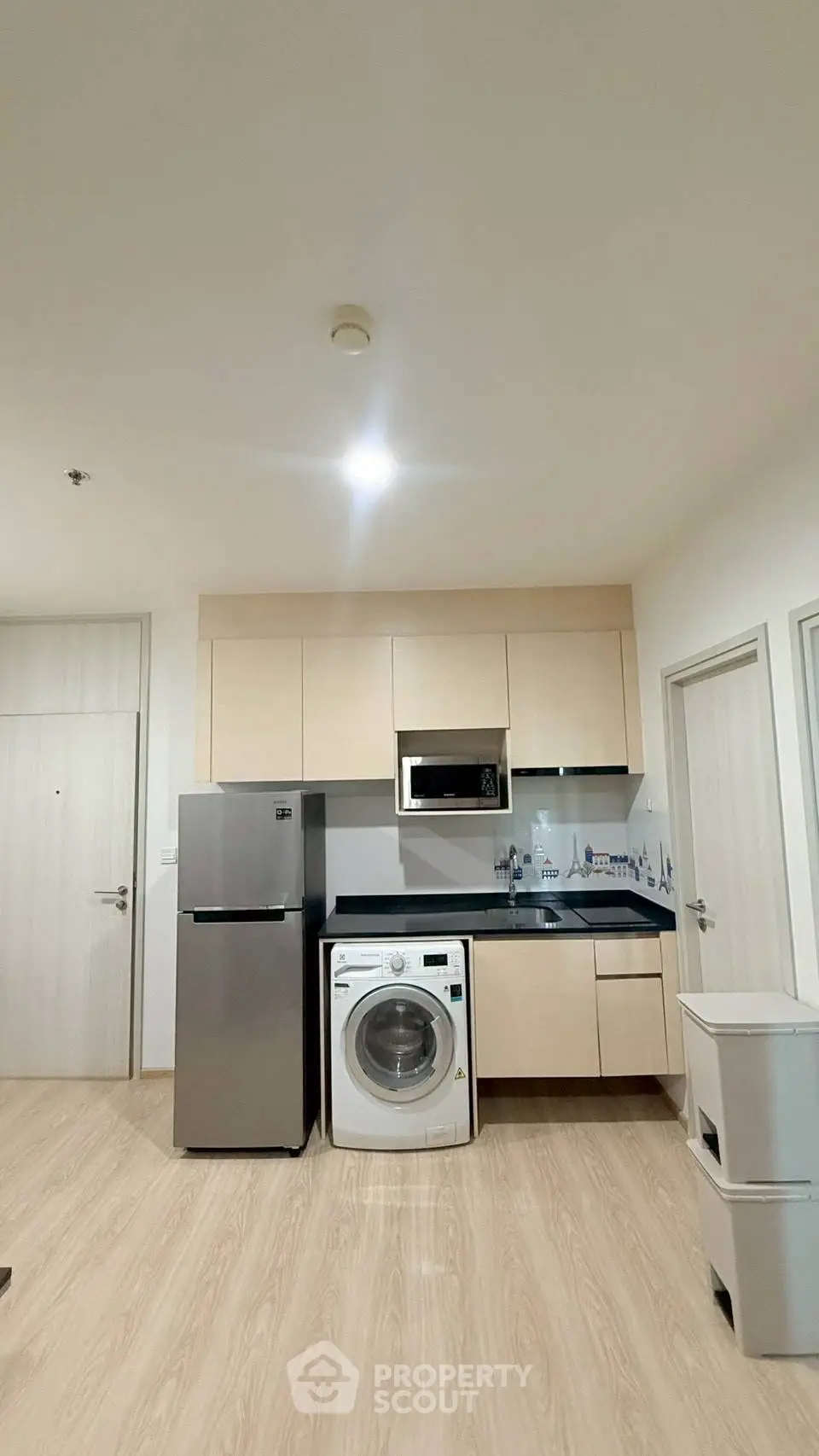 Modern kitchen with washing machine and fridge in compact apartment