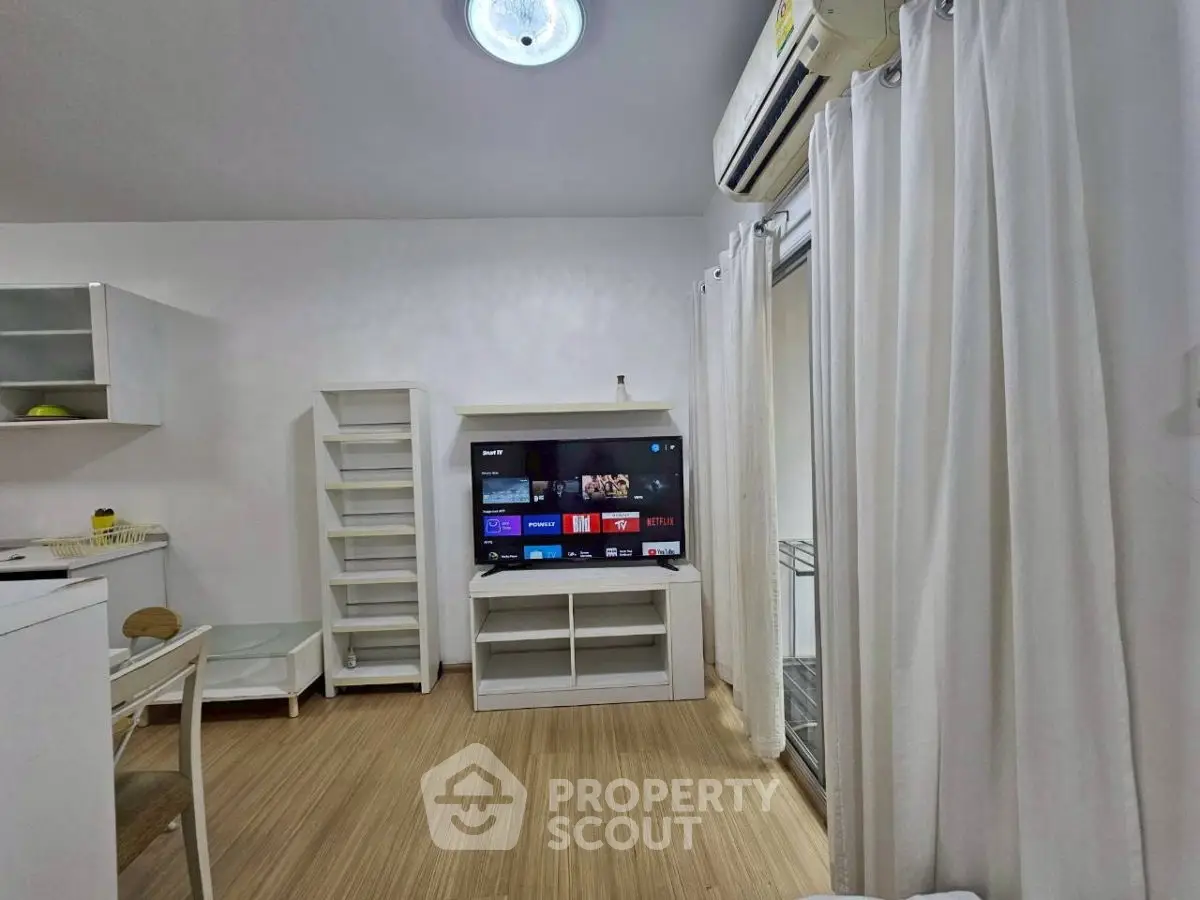 Modern living room with TV, air conditioning, and elegant white curtains.