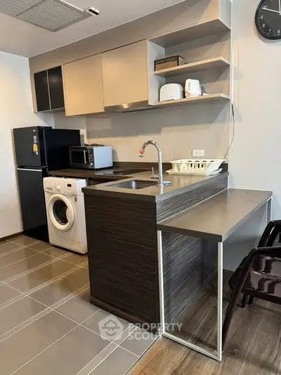 Modern kitchen with sleek cabinetry, washing machine, and appliances in a compact layout.