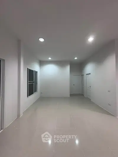 Spacious empty room with modern lighting and tiled flooring, ideal for customization.