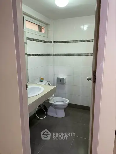 Compact bathroom with modern fixtures and tiled walls, ideal for urban living.