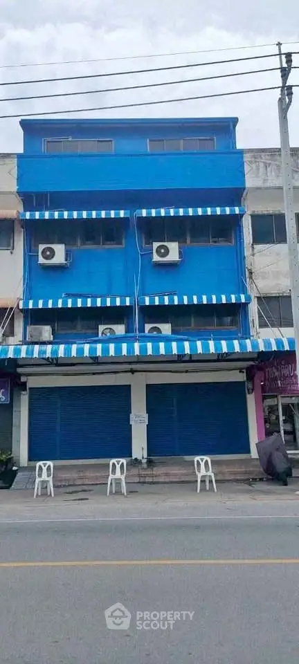 Commercial building with blue facade and closed shutters on a busy street, ideal for business opportunities.