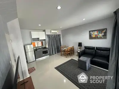 Modern open-layout living room with kitchen and dining area, featuring sleek furniture and stylish decor.