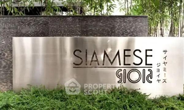 Elegant entrance sign of Siamese Gioia surrounded by lush greenery.