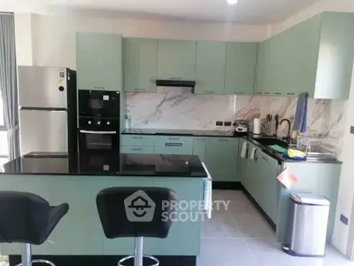 Modern kitchen with sleek cabinetry, marble backsplash, and stainless steel appliances in a stylish apartment.