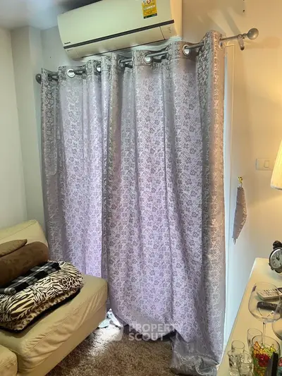 Cozy living room corner with elegant curtains and air conditioning unit.