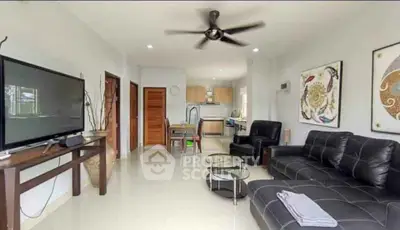 Modern living room with sleek black furniture, open kitchen layout, and stylish decor.