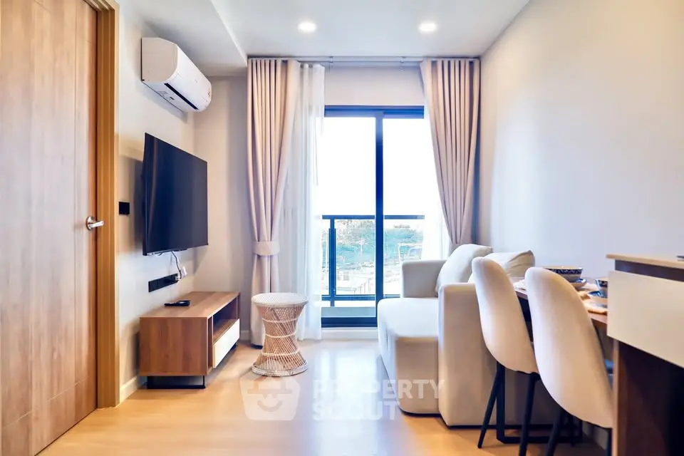Modern living room with balcony view, stylish furniture, and natural light.