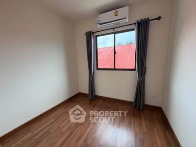 Bright empty room with wooden flooring and air conditioning, ideal for customization.