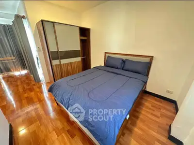 Cozy bedroom with wooden flooring and modern wardrobe in a stylish apartment.