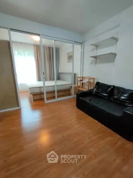 Modern apartment with cozy living room and bedroom separated by glass doors.