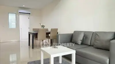Modern living room with sleek furniture and dining area in open layout apartment.