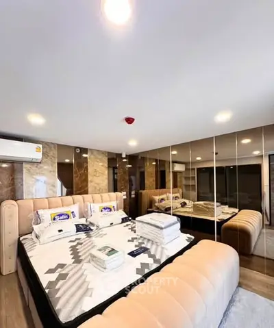 Luxurious bedroom with plush bed, mirrored walls, and modern lighting in a high-end apartment.